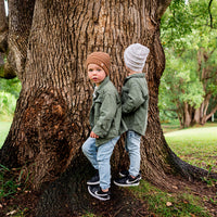 Two children wearing Mocha and Speckle Byron Beanies together beside a tree
