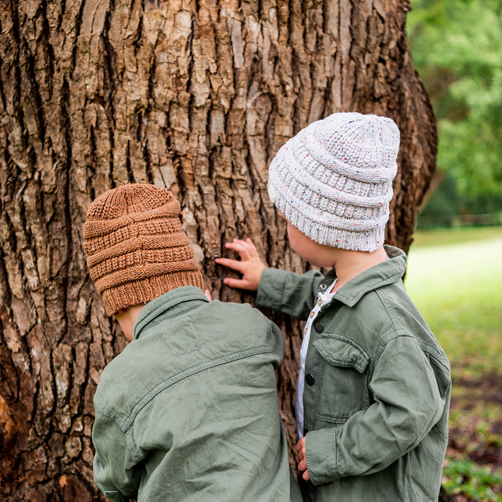 Children wearing Mocha and Speckle Byron Beanies while playing beside a tree