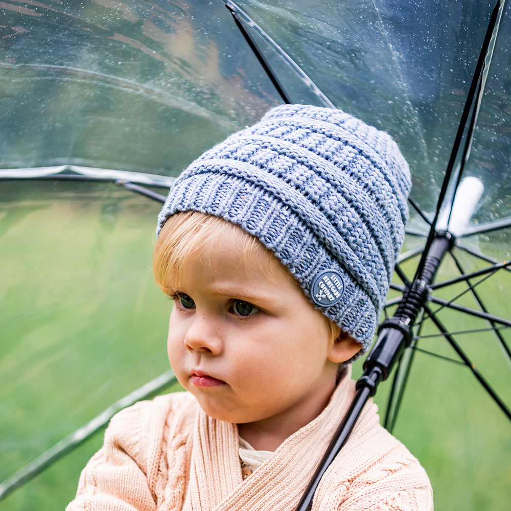 Child wearing the Slate Byron Beanie outdoors beside a clear umbrella
