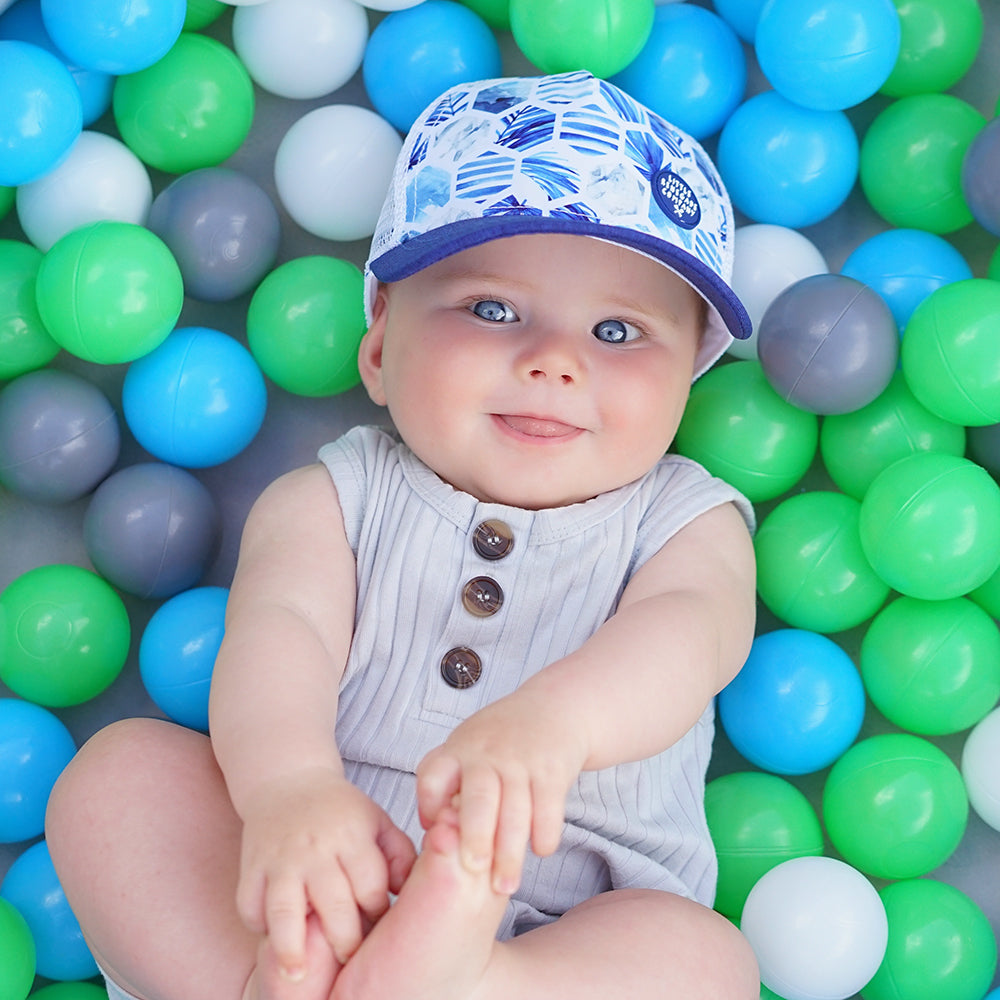 Child wearing the Azure Trucker Cap showing its ocean-blue front, navy peak and breathable white mesh