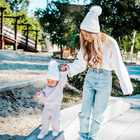 Adult and toddler wearing White Aurora Beanies while walking together outdoors
