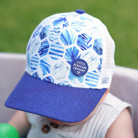 Close-up of a baby wearing the Azure Trucker Cap, showing the blue geometric-leaf print and navy curved peak