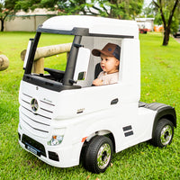 Toddler wearing the Chocolate Trucker Cap while riding in a white toy truck outdoors