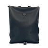 A sleek black totepack made from textured vegan leather with a minimalist design. The bag features a subtle circular logo with "Little Renegade Company" in the center. There is a zipper at the bottom of the bag, indicating the unique shake-out base. The totepack has a clean and modern appearance, ideal for versatile use.