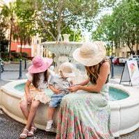 Adult wearing the Oatmeal Sun Hat with children during a family outing by a fountain