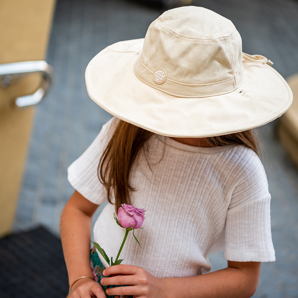 Child wearing the Oatmeal Sun Hat outdoors with the wide brim shading her face