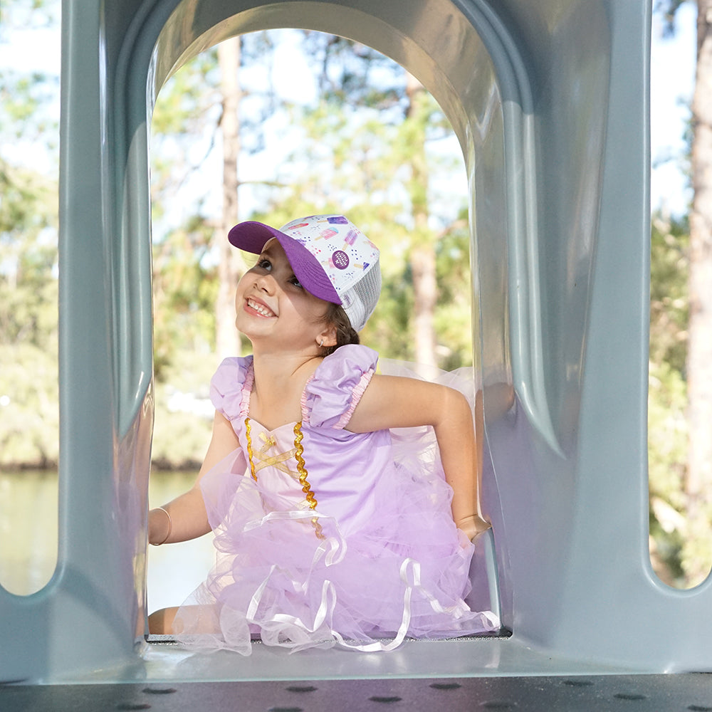 Child wearing the Popsicle Trucker Cap during outdoor play in a purple outfit