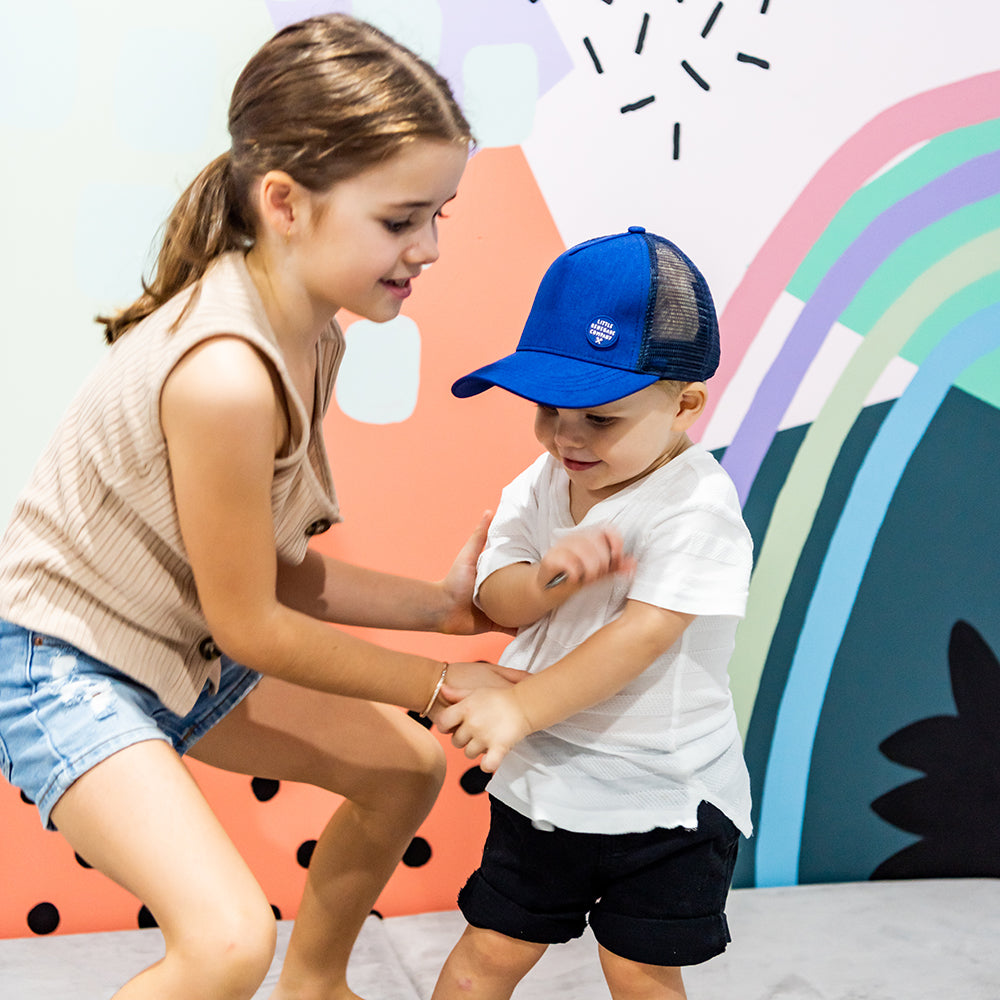 Two children playing while one wears the Sailor Trucker Cap