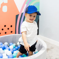 Child wearing the Sailor Trucker Cap while playing in a ball pit