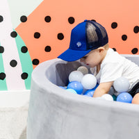 Child wearing the Sailor Trucker Cap during play, showing its royal blue front and navy mesh side