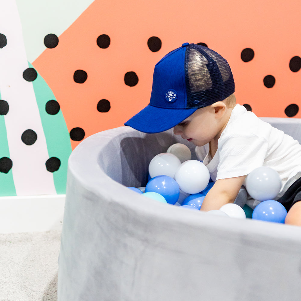 Child wearing the Sailor Trucker Cap during play, showing its royal blue front and navy mesh side