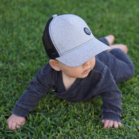 Close-up of a child wearing the Shadow Trucker Cap showing its textured grey front, curved peak and black mesh