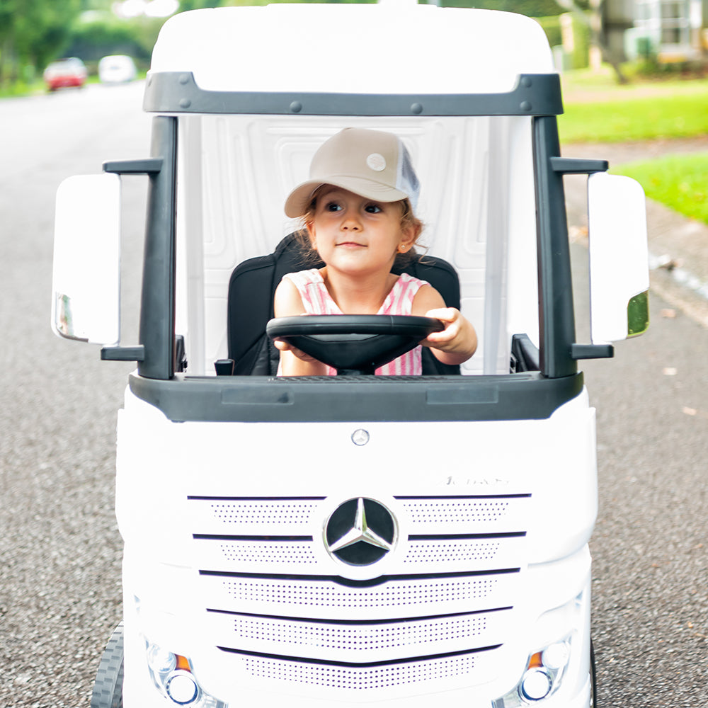 Child wearing the Wheat Trucker Cap while playing in a ride-on car