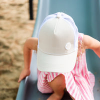 Close-up of a child wearing the Wheat Trucker Cap showing its wheat-toned front, curved peak and white mesh