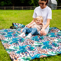 Family relaxing together on the Wild Adventure Mat on the grass