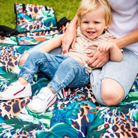 Child sitting on the Wild Adventure Mat showing its colourful leopard and tropical leaf print