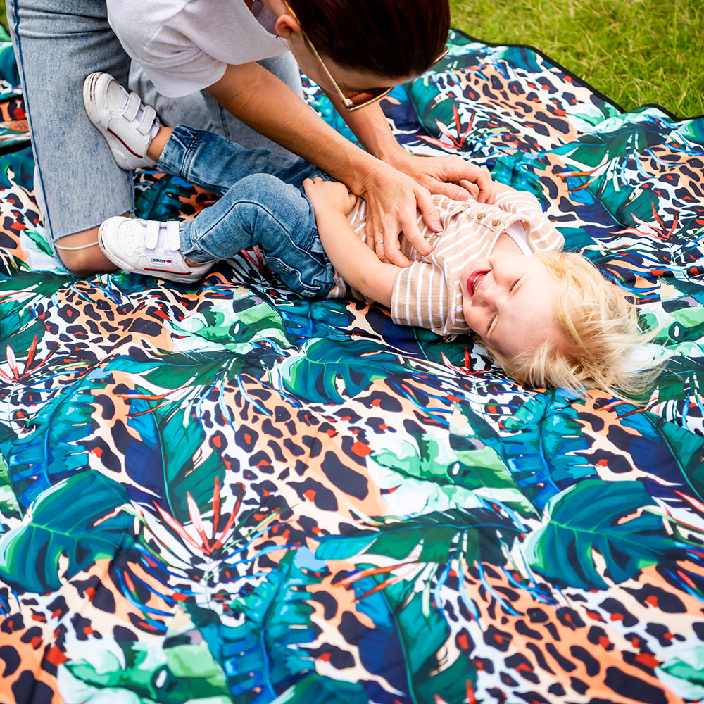 Child sitting on the Wild Adventure Mat outdoors